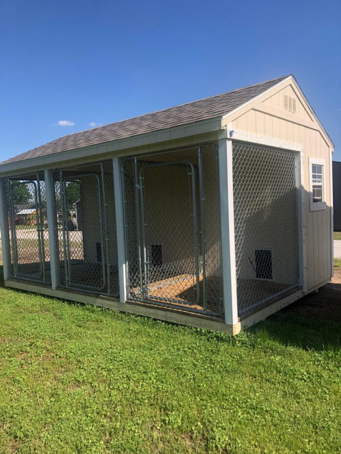 Navajo White 10x16 enclosed dog kennel with a gable roof, three chain-link outdoor runs, two windows, and Navajo White siding with white trim.