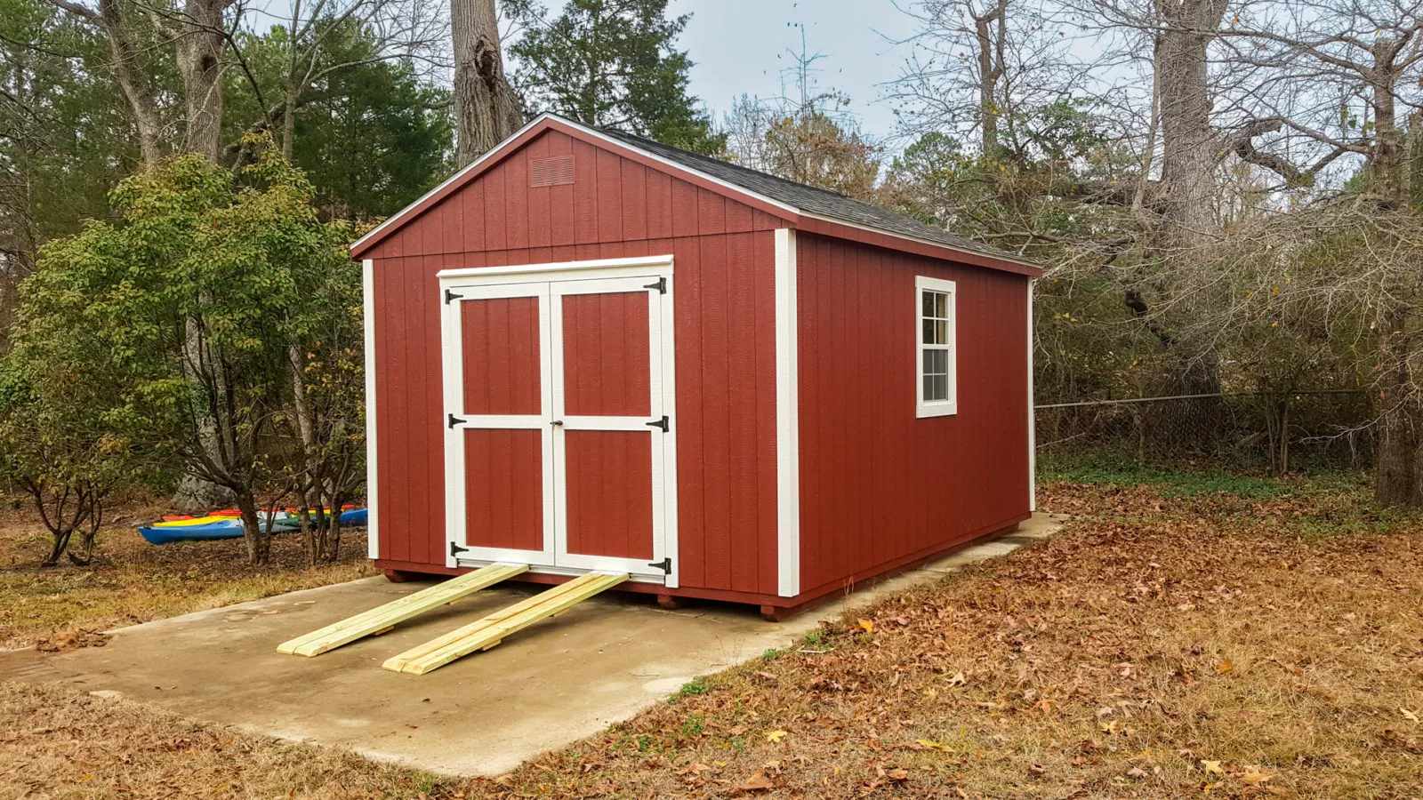 exterior of red and white pre-built storage shed for sale near woods